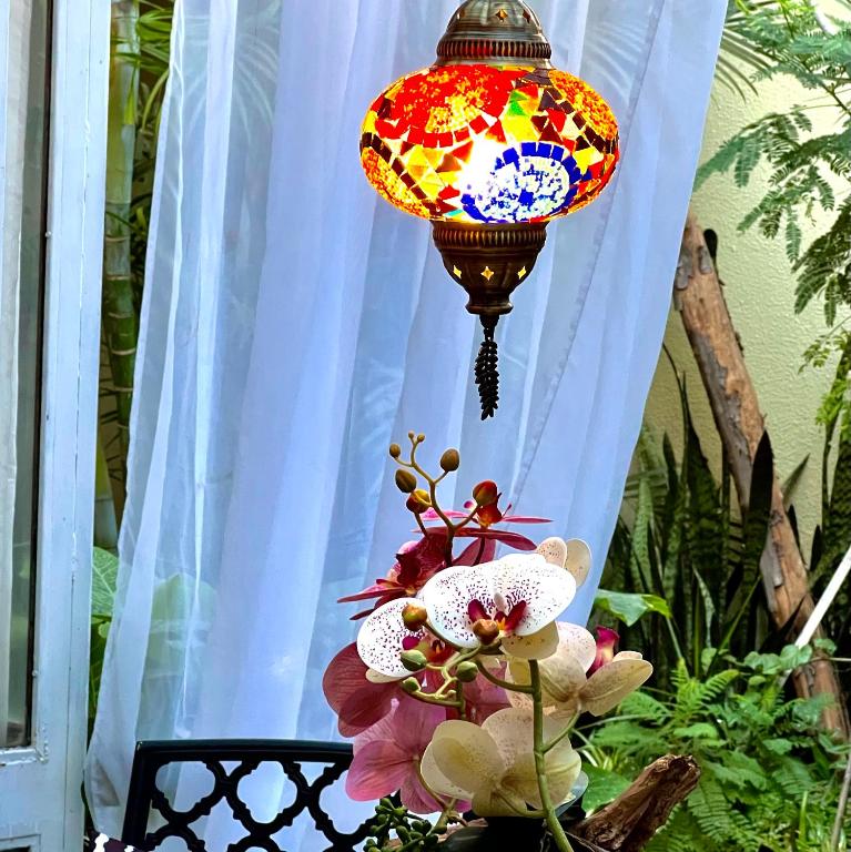 a colorful lamp hanging from a window with flowers at Dickinson Guest House, Guadalajara Expo in Guadalajara