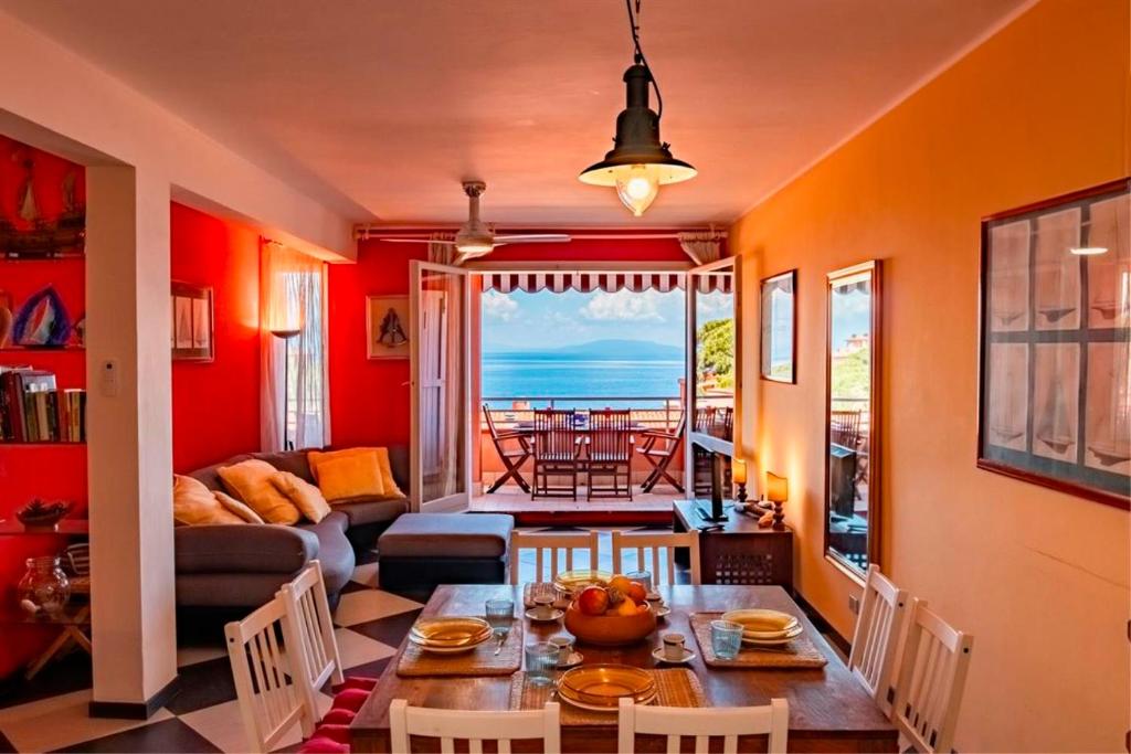 a living room with red walls and a table and chairs at Appartamento Vista Mare - Spriano in Rio Marina