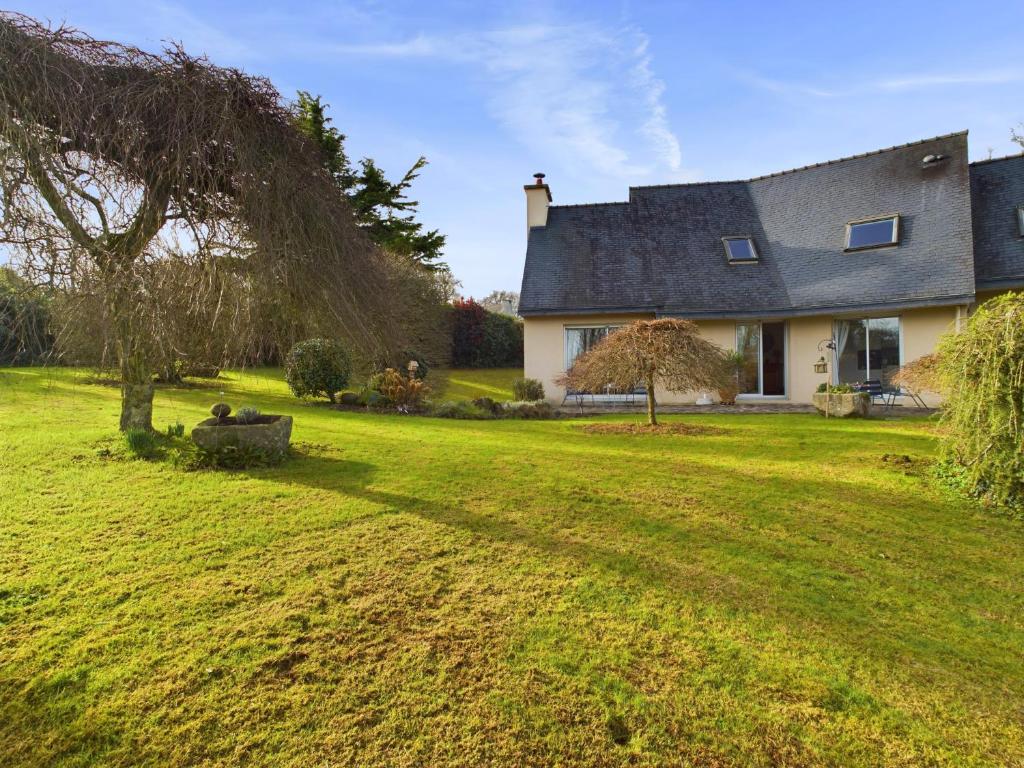 a house with a large yard with a tree at Grande maison spacieuse et moderne avec jardin in Fouesnant