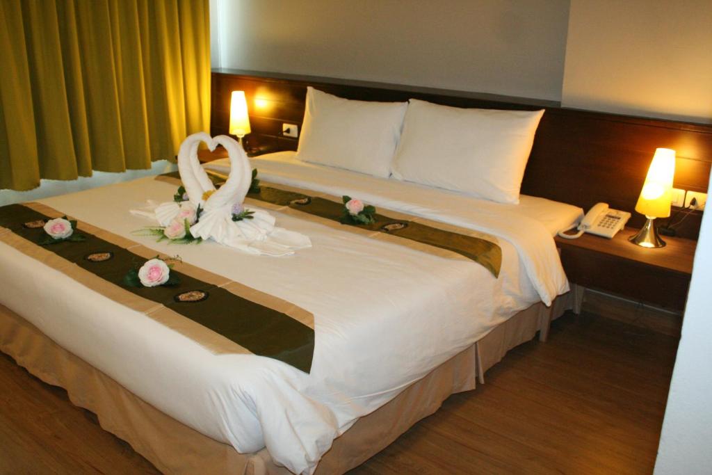 ein Hotelzimmer mit einem großen Bett mit einem Brautstrauß darauf in der Unterkunft Aloha Hatyai Hotel in Hat Yai