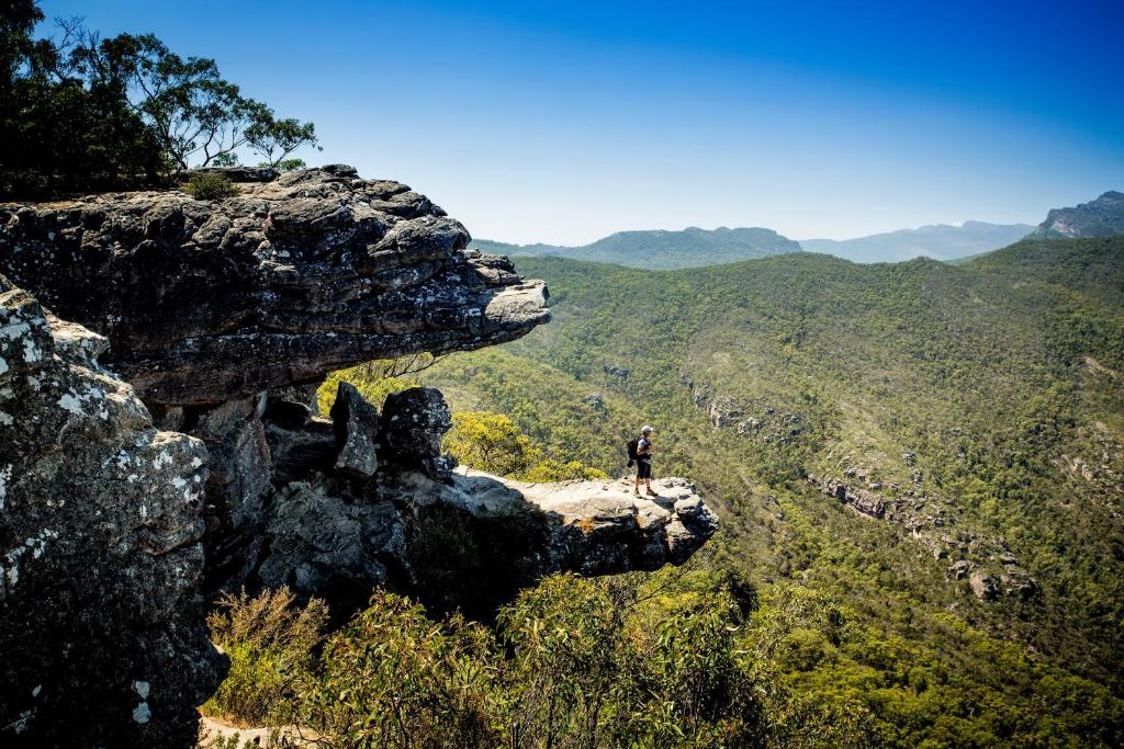 un hombre parado en la cima de una montaña rocosa en NRMA Halls Gap Holiday Park, en Halls Gap