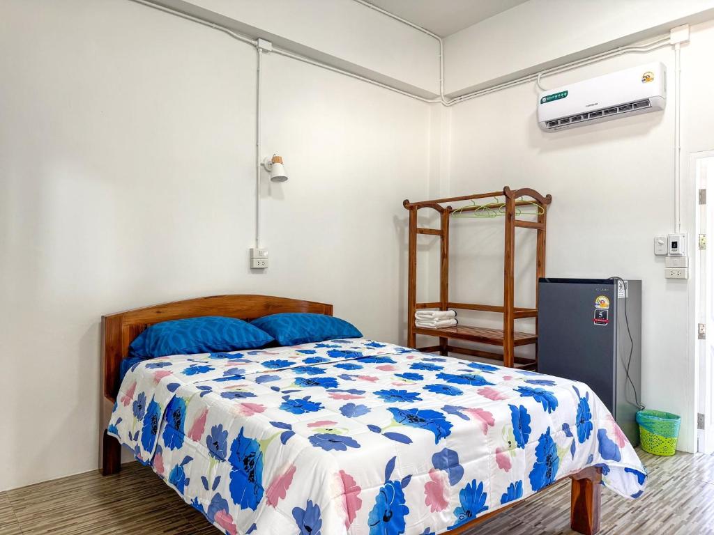 a bedroom with a bed with a blue and white comforter at Jira Hotel in Lampang