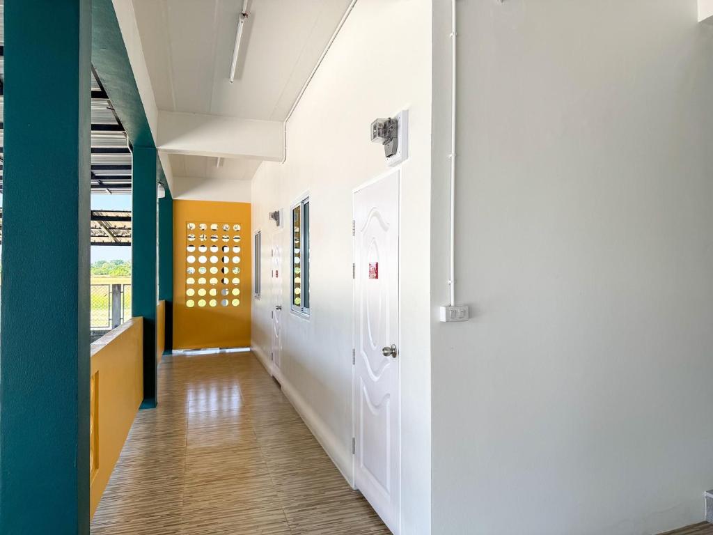 a hallway with white walls and blue and yellow walls at Jira Hotel in Lampang
