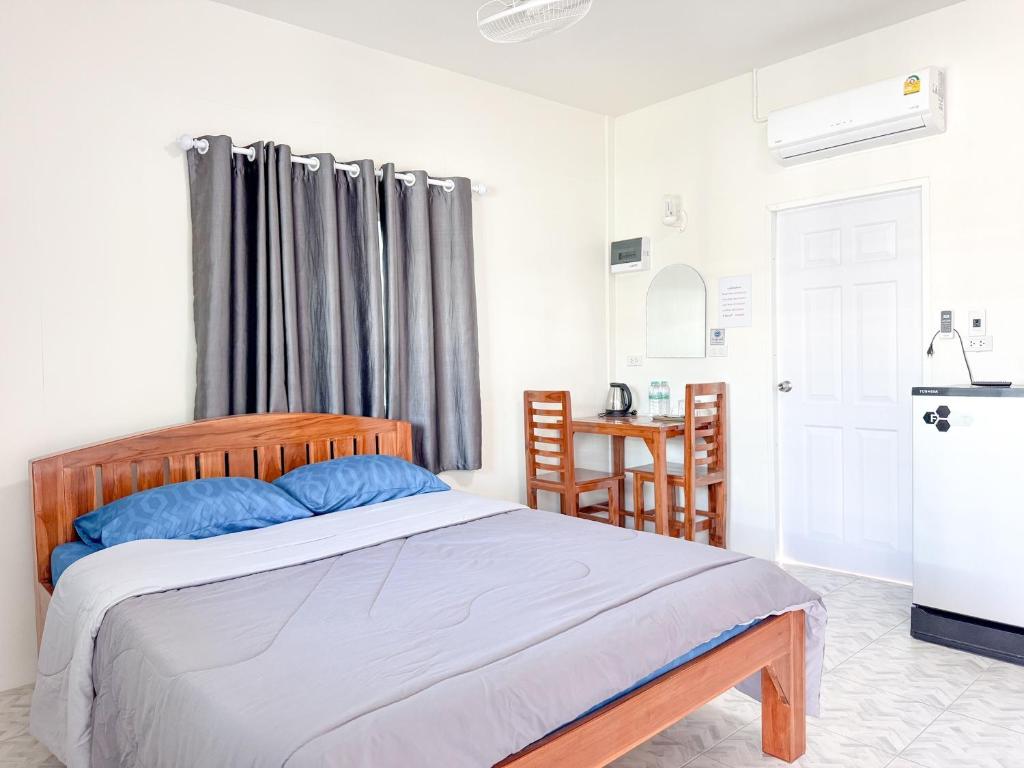 a bedroom with a bed with blue pillows and a refrigerator at Jira Hotel in Lampang