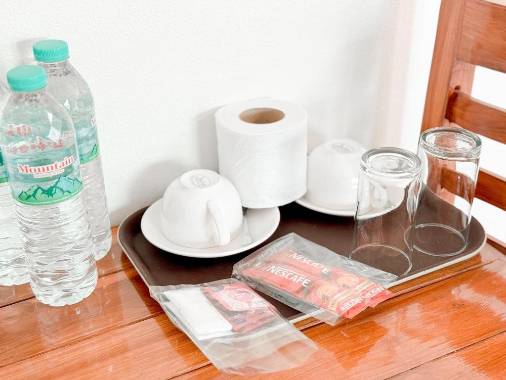 a table with a bottle of water and a plate with toilet paper at Jira Hotel in Lampang