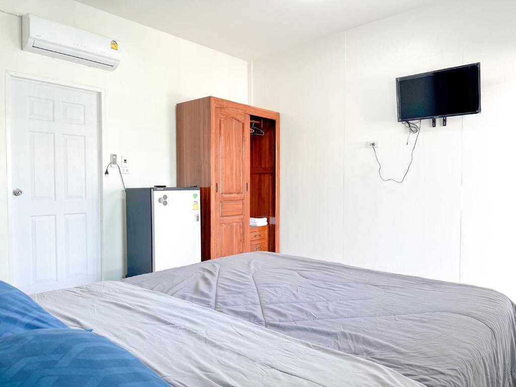 a bedroom with a bed and a tv and a refrigerator at Jira Hotel in Lampang