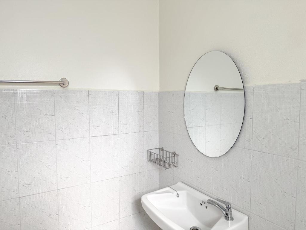 a white bathroom with a sink and a mirror at Jira Hotel in Lampang