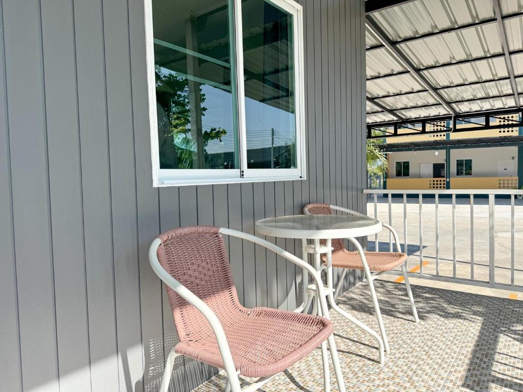 a patio with two chairs and a table and a window at Jira Hotel in Lampang