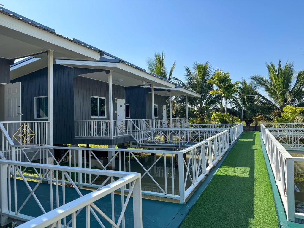 a house with white railings and palm trees at Jira Hotel in Lampang