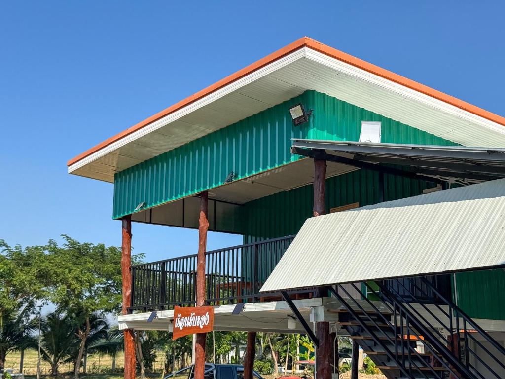 a green and white building with white roofs at Jira Hotel in Lampang