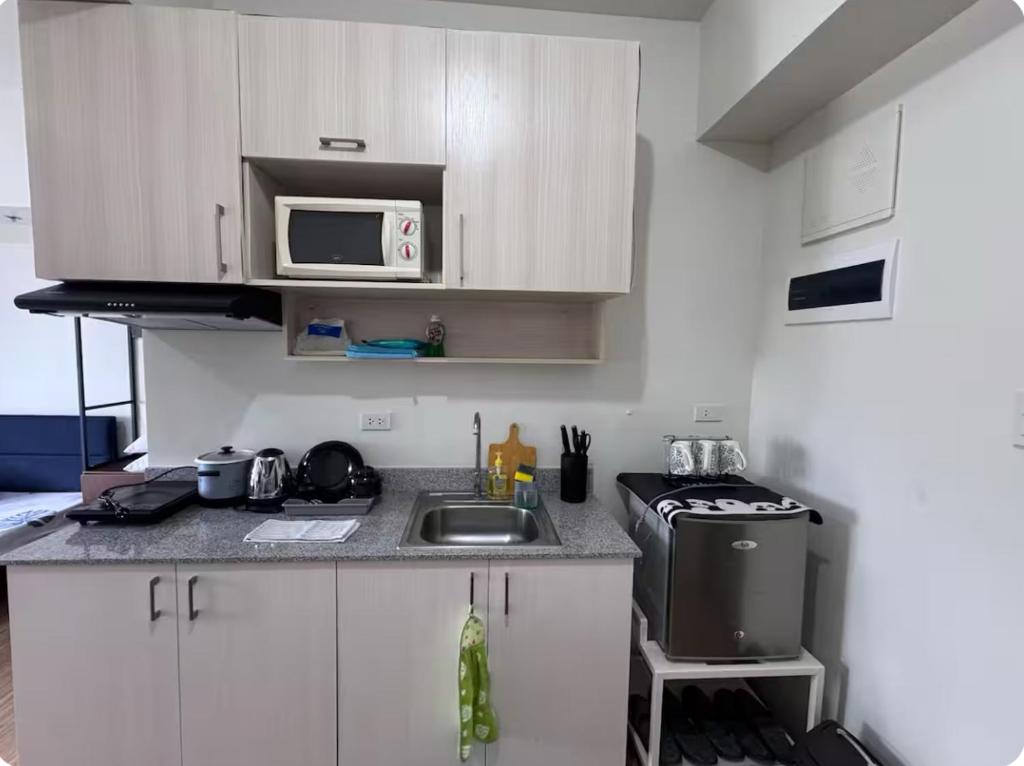 una piccola cucina con lavello e microonde di Tulip Garden Apricot Bldg 1BR with pool and Gym a Biñan