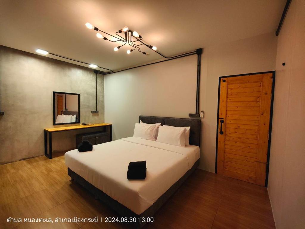 ein Schlafzimmer mit einem weißen Bett und einer Holztür in der Unterkunft Cactus Villa 2024, Krabi in Klong Muang Beach