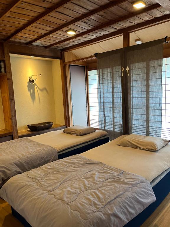 a bedroom with two beds and a wall with a picture at 檸檬草ー奄美の自然の香る宿ー in Amami