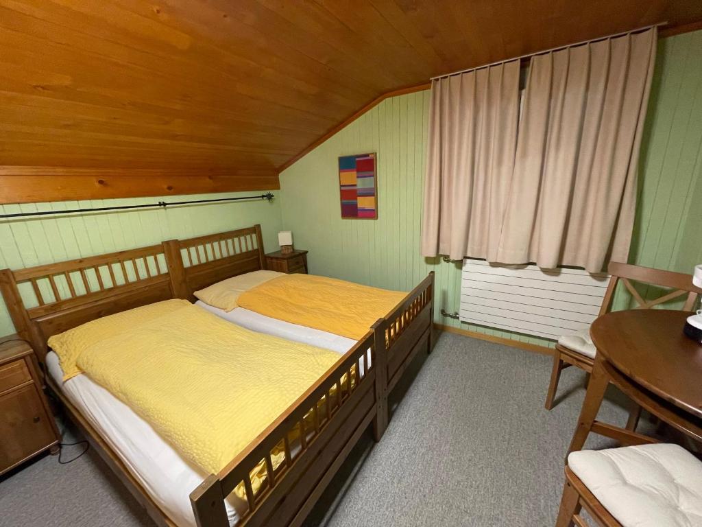 a bedroom with two beds and a table and a window at Long & Short Stay Hotel Bahnhof Ausserberg in Ausserberg