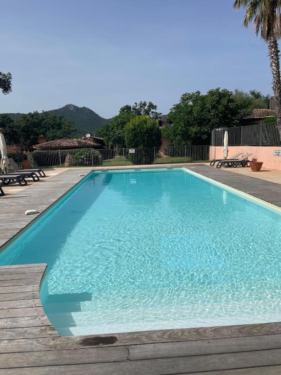 une grande piscine bleue avec une terrasse en bois dans l'établissement Villa La Rotondo dans la résidence ALTA STRADA piscine partagée chauffée, à Sainte-Lucie de Porto-Vecchio