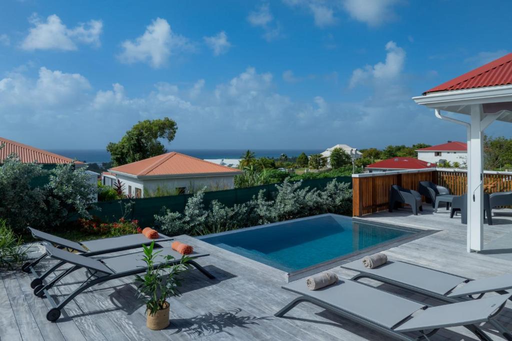 Un patio con piscina y sillas y una casa. en Villa Paloma, en Grand-Bourg