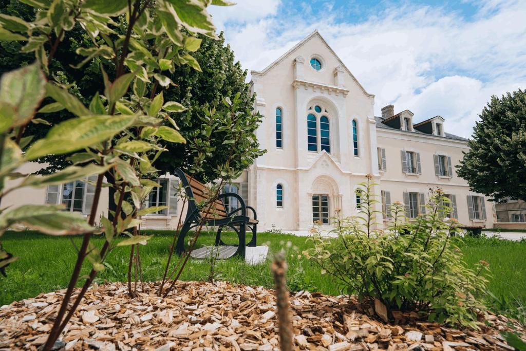 un grand bâtiment blanc avec un banc devant lui dans l'établissement Appart hotel Saint-Denis, à Châteauroux
