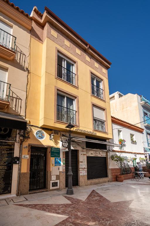 a yellow building with balconies on a city street at Apartamentos Capricho del Mar in Torremolinos