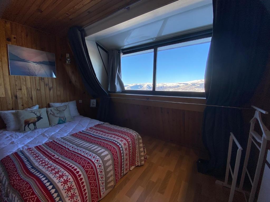 ein Schlafzimmer mit einem Bett und einem großen Fenster in der Unterkunft Appartement face aux montagnes - Belle étoile in Eyne