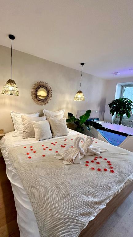 Elle comprend un grand lit blanc avec des coeurs rouges. dans l'établissement L Anaya Nantes Spa et Sauna, à Rezé