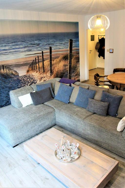 a large couch in a living room with a beach mural at Cosy gezellig app met aparte gastenkamer op 30meter van strand privé garage in Koksijde