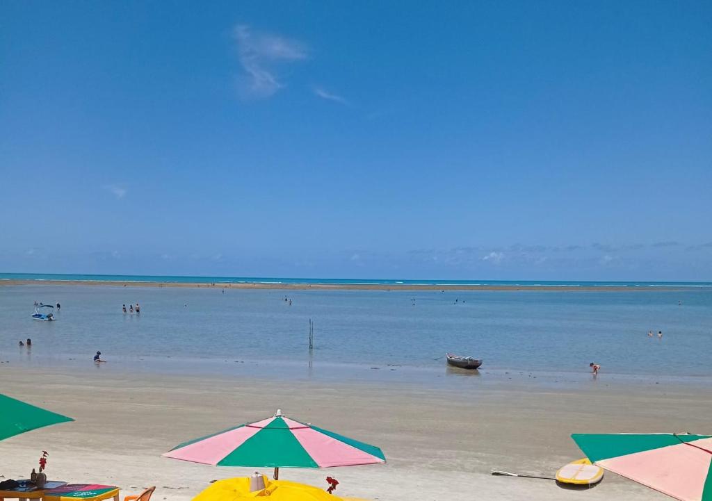 a beach with umbrellas and people in the water at Suítes Nina e Malu in Santa Cruz Cabrália
