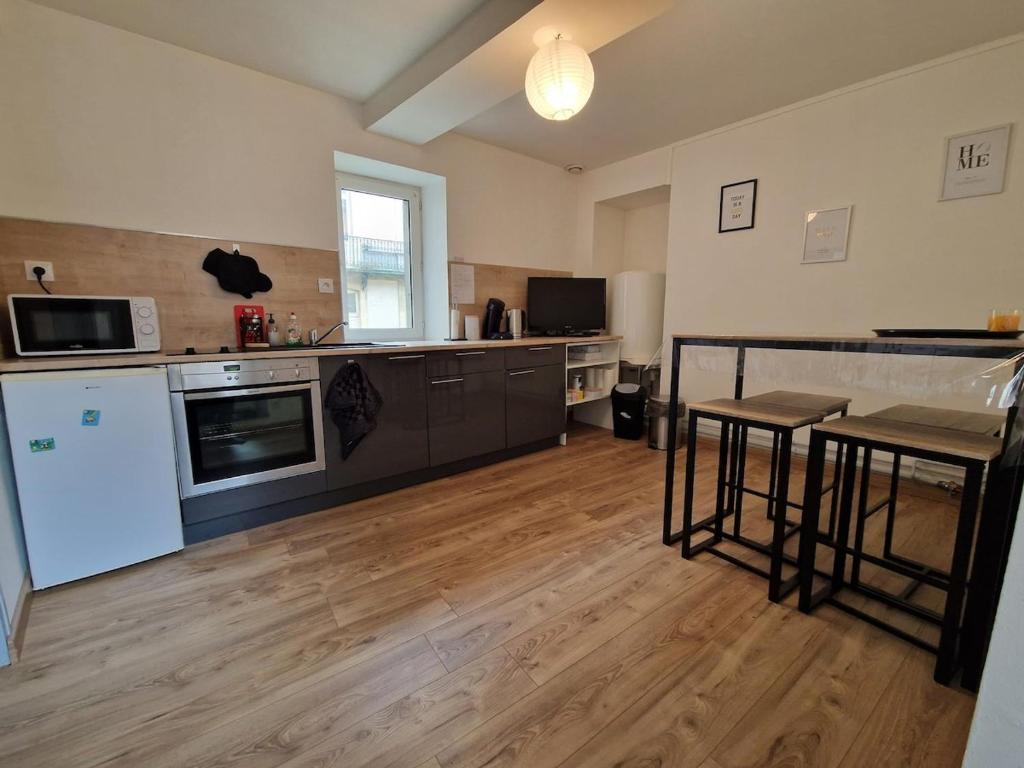 Il comprend une grande cuisine avec du parquet et des appareils électroménagers. dans l'établissement Appartement atypique au cœur de Gray, à Gray