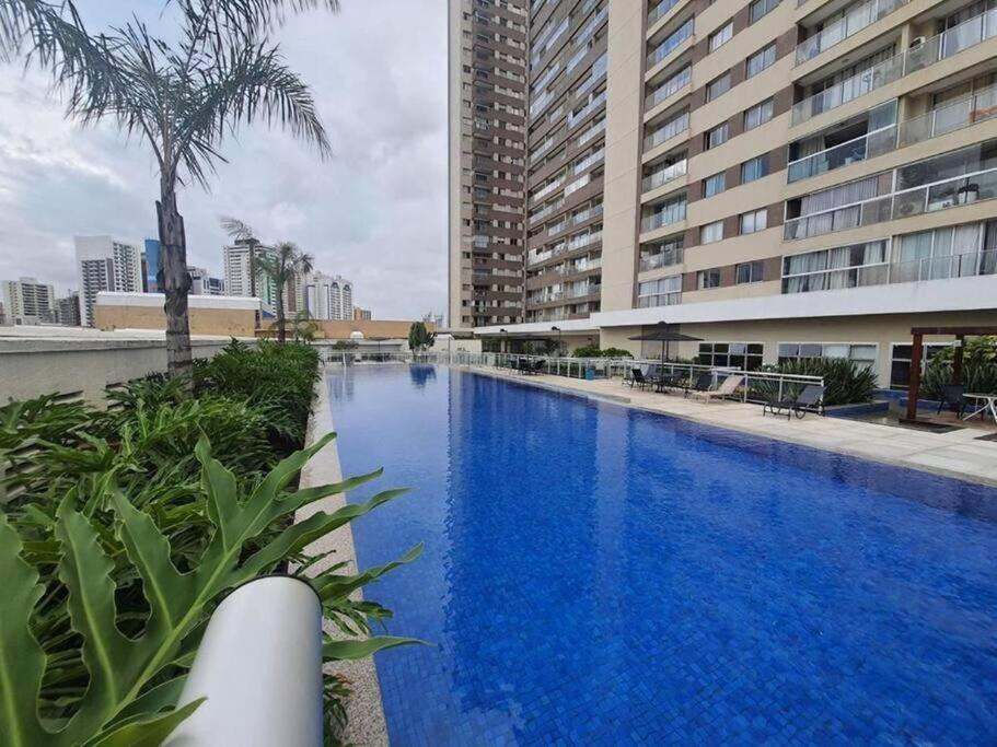 a large blue swimming pool next to a tall building at Apartamento no Shopping em Brasília DF in Brasilia