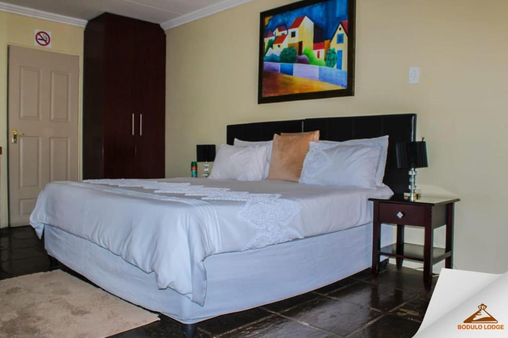a bedroom with a large white bed and a table at Bodulo Lodge in Thaba Nchu