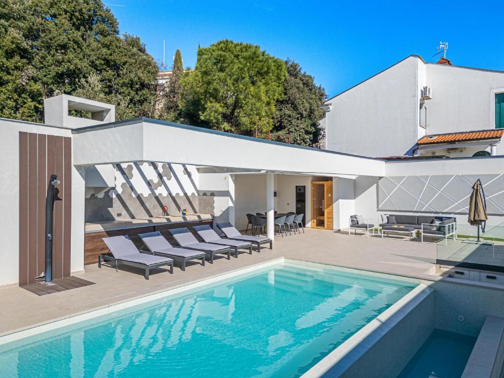 a swimming pool with chairs and a house at Villa Incanto in Pješčana Uvala 
