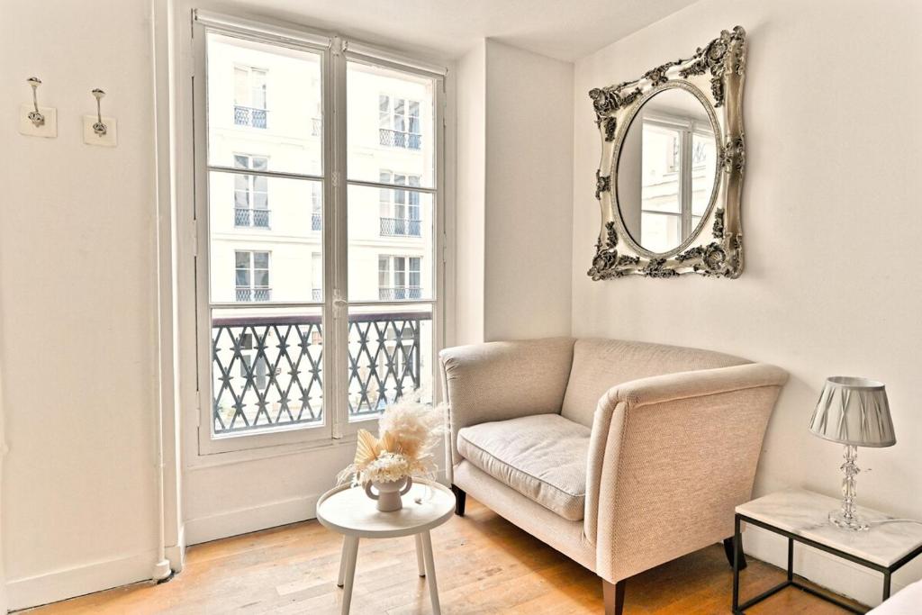 un salon avec une chaise et un miroir dans l'établissement Pleasant Apartment Close to Galerie Lafayette - II, à Paris