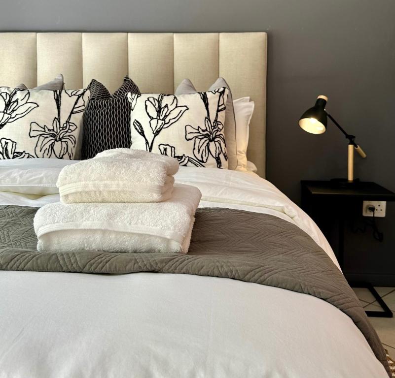 a bedroom with a white bed with black and white pillows at Pass-through Apartments in Pretoria