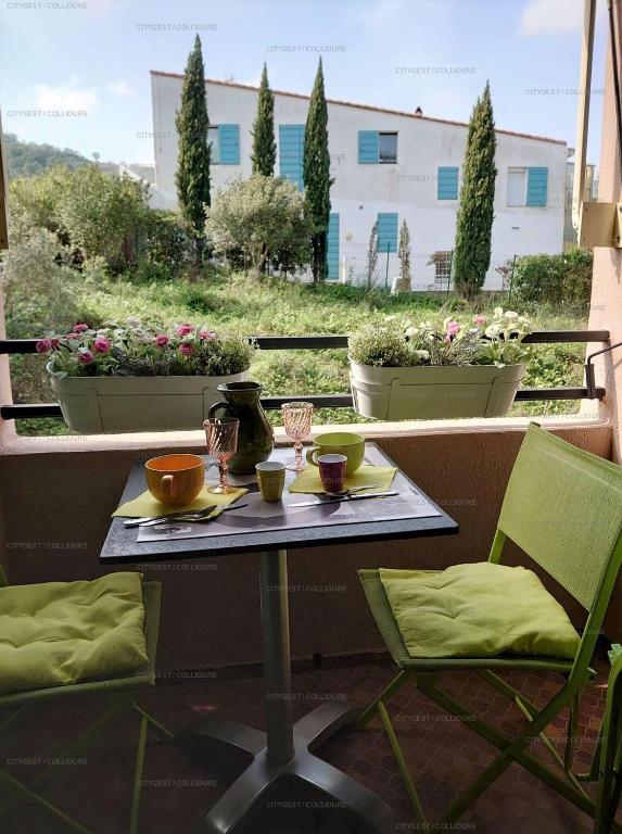 - une table sur un balcon avec 2 chaises et des tasses dans l'établissement 3PA45 - Très confortable T2 avec terrasses dans résidence avec piscine et parking, à Collioure