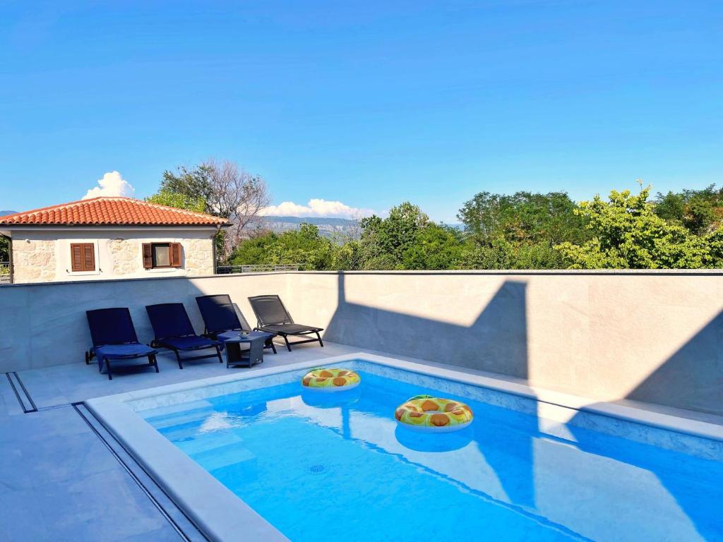 a swimming pool with two chairs at Apartment Bonum with Private Pool in Šilo
