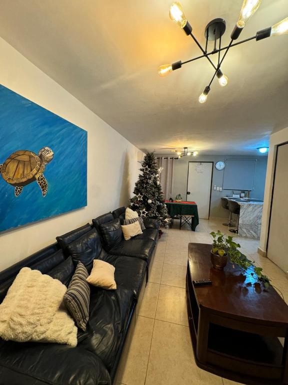 a living room with a black leather couch and a christmas tree at Yes's house in Monterrey