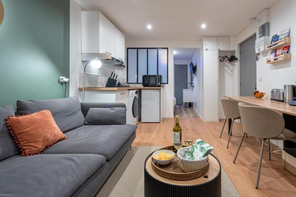 a living room with a couch and a table and a kitchen at Cozy Jacuzzi Bordeaux Chartrons in Bordeaux