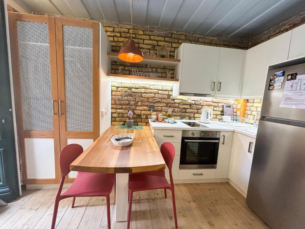 una cucina con un tavolo di legno con sedie e un frigorifero di Kukuvayia's Nest-Centre Old Town Corfu a Città di Corfù