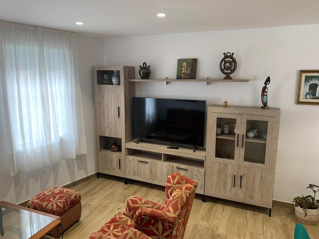 a living room with a entertainment center with a flat screen tv at Casa Conricado in O Grove