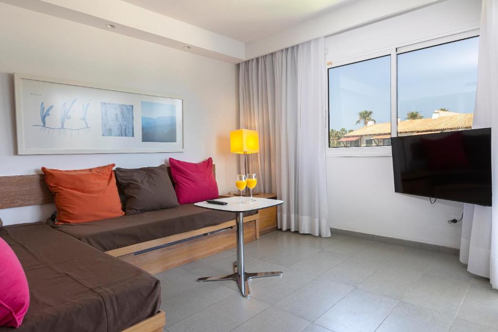 Una sala de estar con un sofá y un televisor. en Hipotels Apartamentos Cala Bona, en Cala Bona