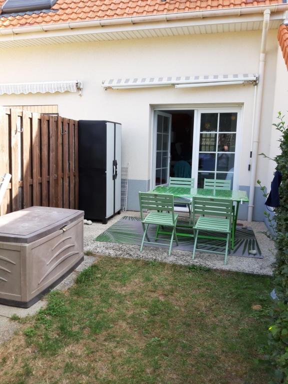 d'une terrasse avec une table, des chaises et un réfrigérateur. dans l'établissement Opal'In, au Crotoy