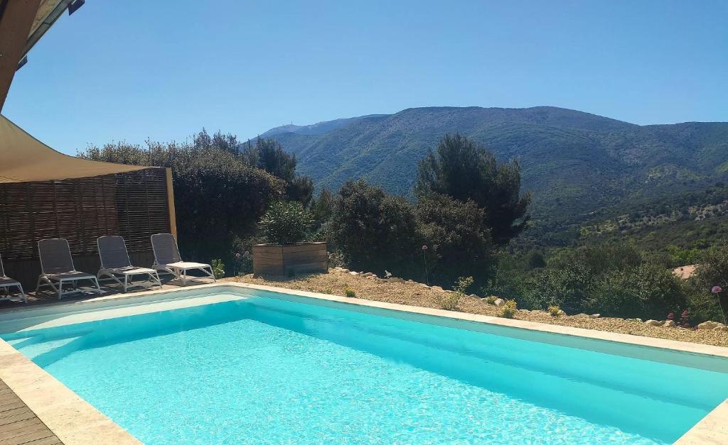 une piscine avec des chaises et des montagnes en arrière-plan dans l'établissement La Bernardière du Ventoux 1, à Mollans-sur-Ouvèze