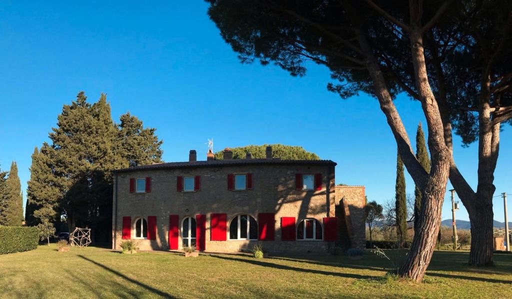 an old house with a tree in front of it at La Casa Rossa in Marina di Bibbona