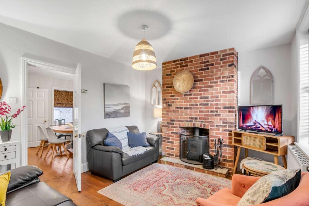 a living room with a brick fireplace and a couch at Bay Tree Cottage - Cozy Norfolk Retreat in Heacham in Heacham