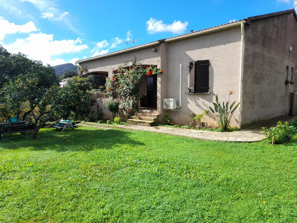 ein kleines Haus mit einem grünen Hof mit einem Gebäude in der Unterkunft Corse Maison de campagne mer et montagne in Sorbo-Ocagnano