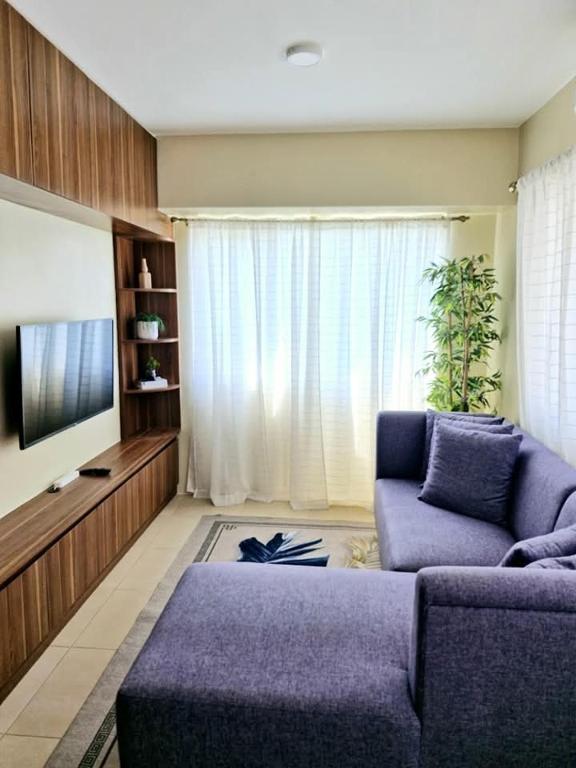 a living room with a purple couch and a tv at Avida Towers 2 Bedroom by PHI Rentals in Iloilo City