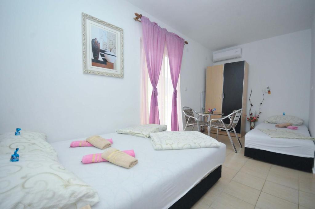 1 dormitorio con 2 camas y una ventana con cortinas rosas en Apartments Nedovic-Jaz, en Budva