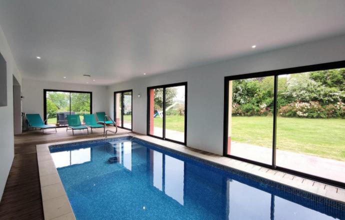 a large swimming pool in a house with windows at Maison avec Piscine intérieure privée sans vis à vis chauffée toute l année in Quiévrecourt