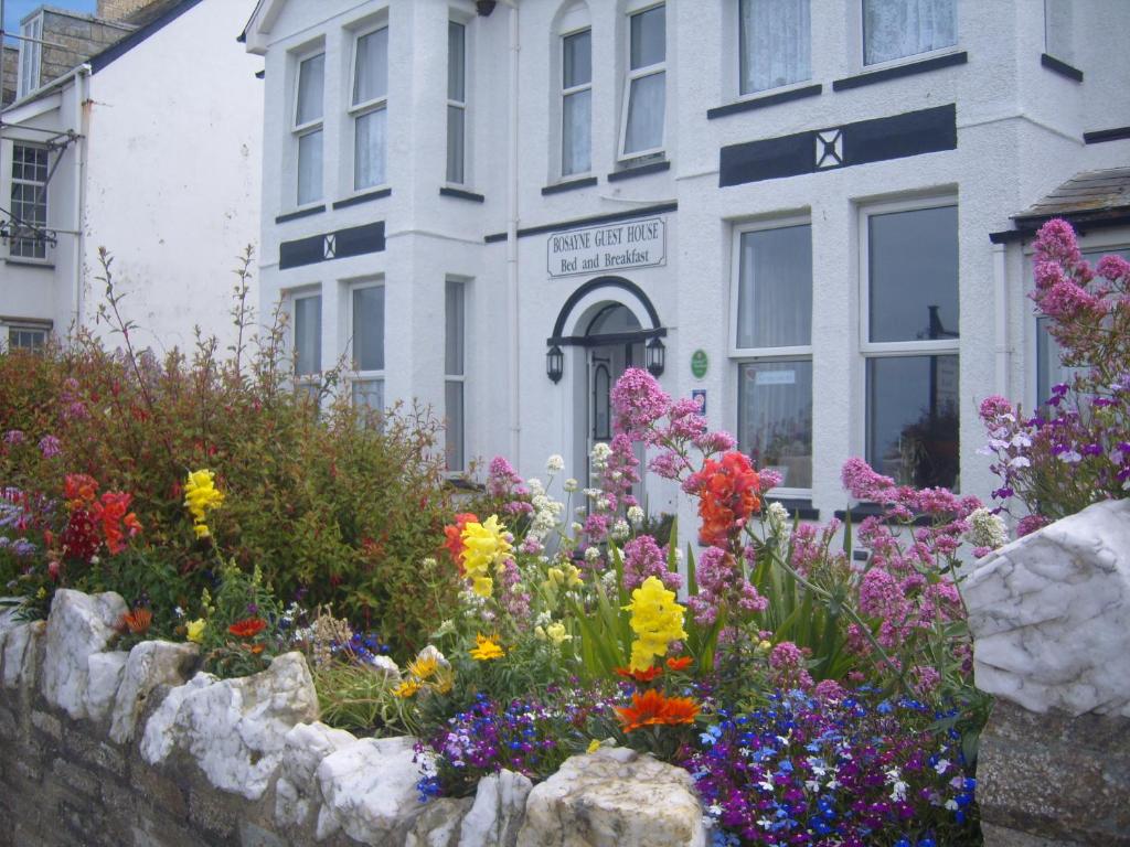 um jardim de flores em frente a um edifício em Bosayne Guest House em Tintagel