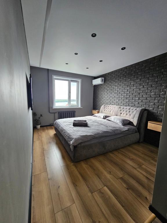 a bedroom with a large bed and wooden floors at Квартира in Pavlodar
