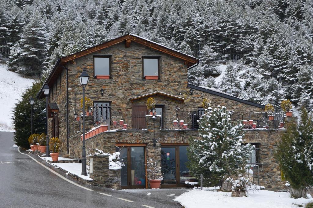 una casa de piedra en la nieve en una montaña en Hotel Parador de Canolich - Only Adults en Bixessarri